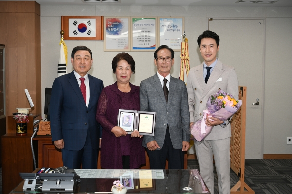 황선봉 군수가 가수 신성 씨에게 공로패를 전달하고 있다.          신성 씨와 아버지, 어머니 사진