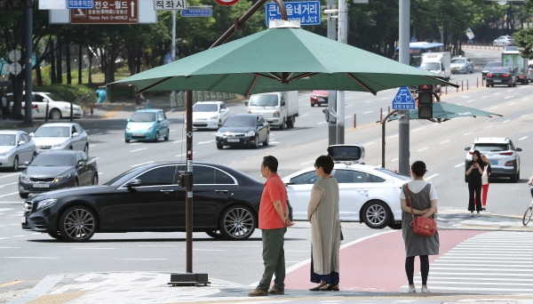 30일 서구 경성큰마을 네거리에 설치된 그늘막 밑에서 오가는 시민들이 발길을 멈추고 더위를 피하고 있다