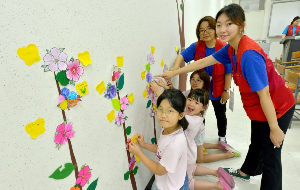 백석쿰캠프에 참석한 초등학생들이 위안부 할머니들이 꽃길을 걷길 바라는 마음을 담아 색칠한 꽃과 편지를 붙이고 있다.