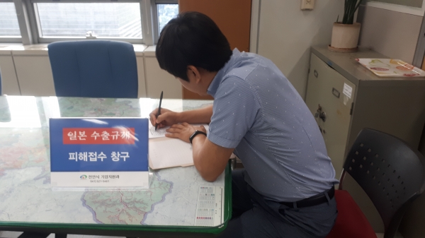 천안시 일본 수출규제 피해기업 접수창구에서 피해 기업 관계자가 신청서를 작성하고 있다.
