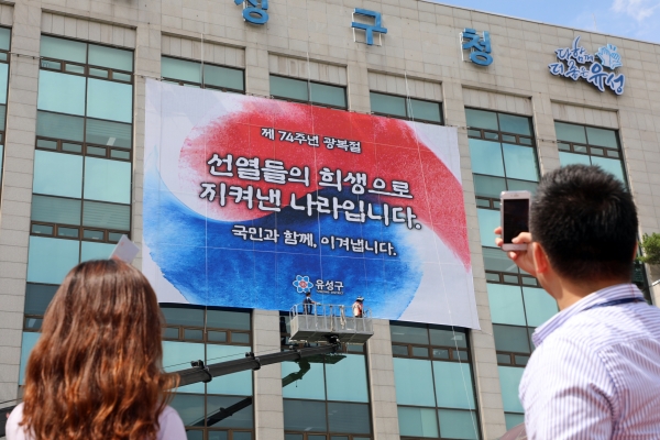 8일 유성구청을 방문한 시민들이 광복절 74주년을 기념해 청사 전면에 걸린 대행 현수막를 보고 있다