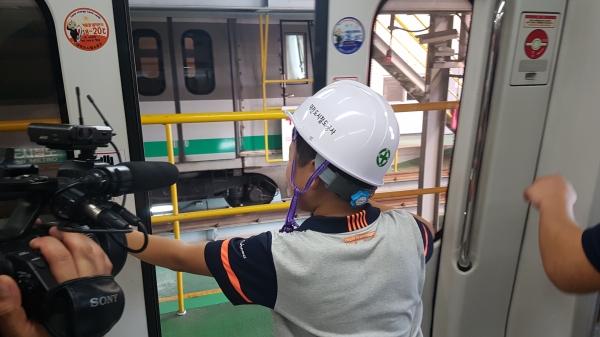 △ 화재 등 비상상황이 발생할 경우 수동으로 전동차 출입문을 열고 탈출하는 체험을 하고 있다.