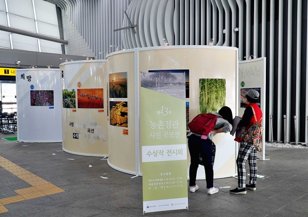 SRT수서역에서 열리고 있는 제13회 농촌경관사진공모전 전시를 역사 이용객이 유심히 보고있다