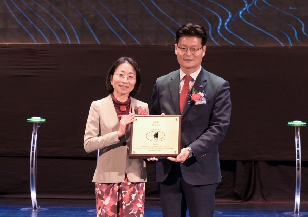 요코 시라이시 국제안전도시 실사단장으로부터 공인패와 휘장을 전달받고 있다.