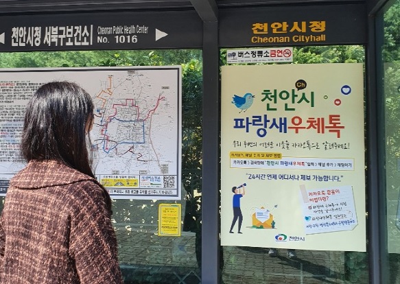 복지사각지대 발굴-버스승강장에 부착된 천안시파랑새우체통 홍보물 보고있는 모습