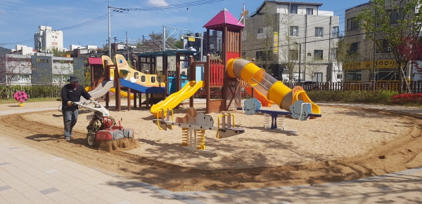 천안시 관계자가 어린이 모래놀이터의 소독을 위해 모래이물질제거 및 모래뒤집기를 하고 있다.