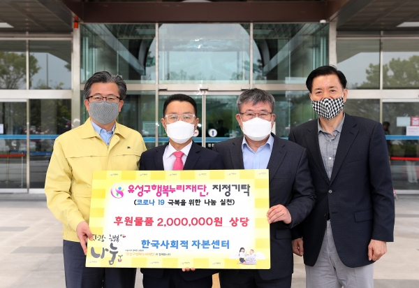 27일 구청 본관 입구에서 한재명 이사장(왼쪽에서 두 번째)과 송윤영 이사(오른쪽에서 두 번째)가 정용래 유성구청장(맨 왼쪽)과 신동천 유성구행복누리재단 상임이사(맨 오른쪽)에게 코로나19 예방을 위한 200만원 상당의 후원물품을 기탁하고 있다