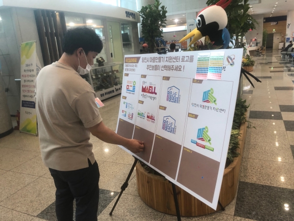 마을만들기 지원센터 로고 주민의견 수렴을 위해 보드판에 스티커를 부착하고 있다.