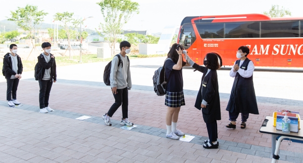 등교하는 학생들의 열체크를 하는 선생님