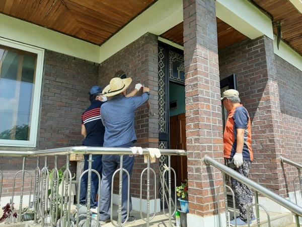 귀농귀촌협의회 회원들이 태극기 걸이와 문패를 설치하는 모습