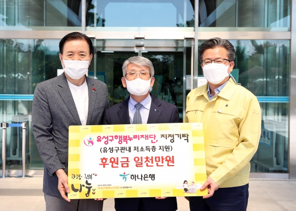1일 구청 본관 입구에서 윤순기 ㈜하나은행 충청영업그룹  총괄대표(가운데)가 정용래 유성구청장(오른쪽)과 신동천 유성구행복누리재단 상임이사(왼쪽)에게 코로나19 피해가정 지원을 위해 후원금 1,000만 원을 기탁하고 있다