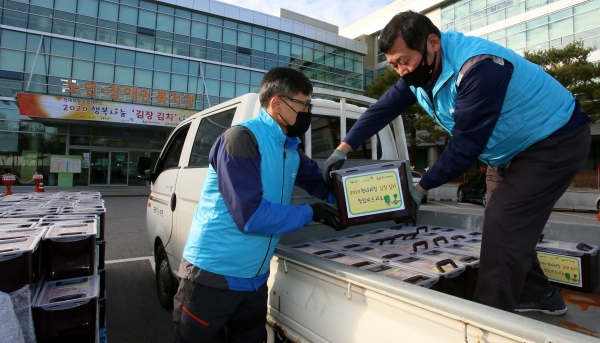 현대제철 당진제철소 직원 봉사자가 당진종합복지타운 광장에서 김장김치를 복지시설 차량에 싣어주고 있다.