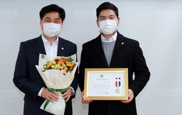 아산시의회 이상덕 의원이 전국 시·군·자치구의회의장협의회 지방의정봉사상을 황재만 의장으로부터 전수 받고 기념촬영하고 있다.