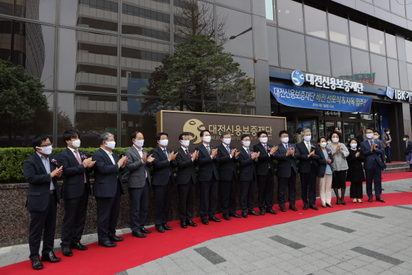 사진 왼쪽부터 대전·세종지방 중소벤처기업청장 조재연 청장, 법무법인 윈 이종오 변호사, 상공회의소 정태희 회장, 대전문화재단 심규익 대표이사, 산업건설위원회 김찬술 위원장, 신용보증재단 중앙회 김병근 회장, 대전광역시 의회 권중순 의장, 대전광역시 김명수 과학부시장, 대전신용보증재단 송귀성 이사장, 대전광역시 중구 황운하 국회의원, 중앙시장활성화 구역상인회 박황순 회장, 목원대학교 권혁대 총장, 국민은행그룹 윤도원 대표, 씨크릿우먼 김영휴 대표, 대전신용보증재단 김수진 노조위원장, TJB대전방송 이광축 대표가 대전신용보증재단 신사옥 현판 앞에서 입주 기념 사진을 찍고 있다.