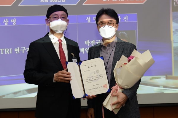 ETRI 국제회의장에서 개최된 창립 45주년 기념식에서 김명준 원장(왼쪽)이 박전규 실장에게 올해의 연구자상을 시상하는 모습.
