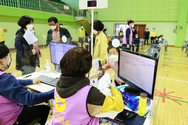 접수창구 요원들이 어르신들의 접종절차 등을 안내하며 접수를 돕는 장면