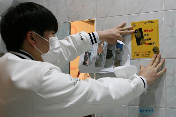 중앙도서관 1층 여자화장실에서 한 학생이 경찰이 제작한 범죄예방 스티커를 붙이고 있다.