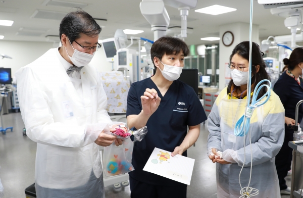 세종충남대병원 나용길 원장(사진 왼쪽)과 소아청소년과 이병국 교수(사진 가운데)가 신생아중환자실에서 치료 중인 아기의 부모에게 어린이날 특별 선물을 전달하며 아기의 상태를 설명하고 있다.