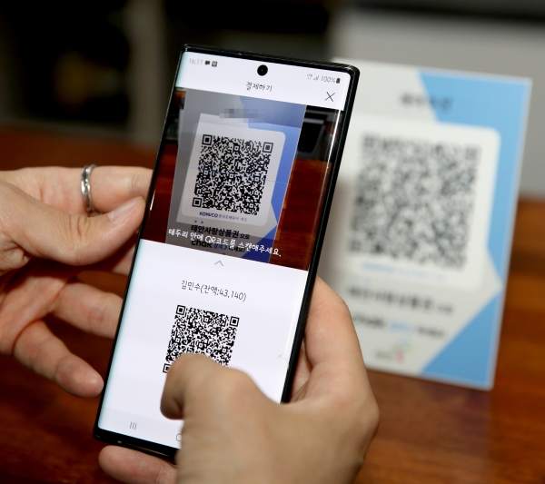 한 주민이 태안사랑상품권 가맹점에서 모바일 결제앱을 살펴보고 있는 모습