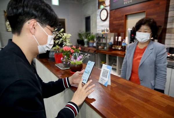 한 주민이 태안사랑상품권 가맹점에서 모바일 결제앱을 살펴보고 있는 모습