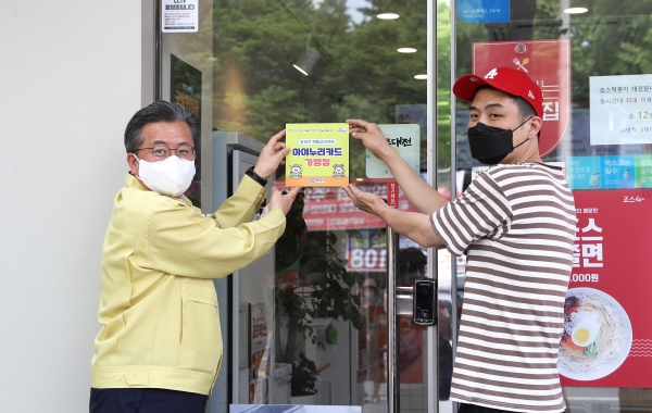 정용래 유성구청장(왼쪽)이 아동급식카드 가맹점을 방문해 아동급식카드 가맹점 스티커를 부착하고 있다.