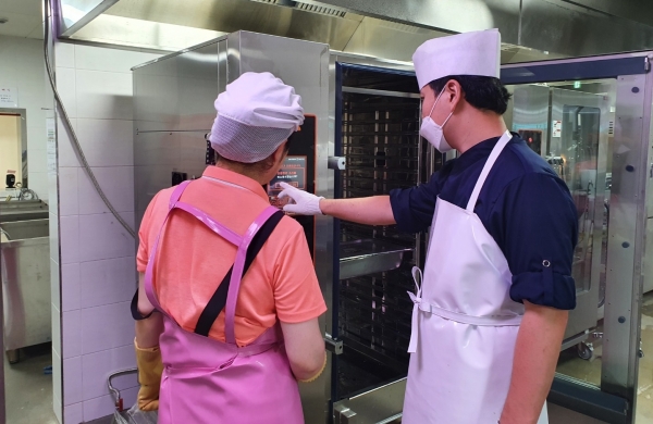 학생식당 조리원들이 새로 도입한 전기오븐기를 이용하여 조리하고 있는 모습