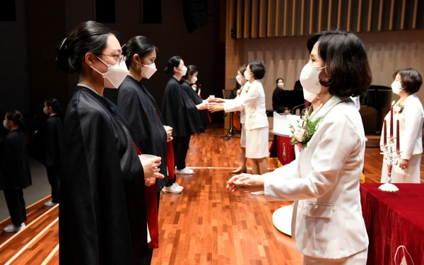 백석대 제11회 나이팅게일 선서식에서 교수가 학생에게 촛불을 전해주고 있다.