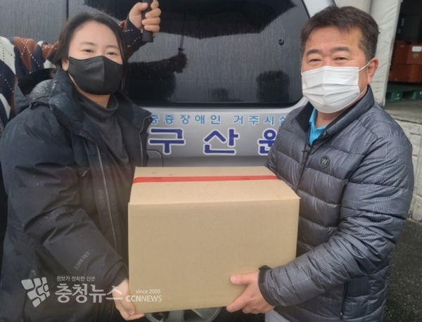 새롬에프에스(주) 노영래 전무(우)가 구산원 직원(좌)에게 사랑의 물품 전달하고 잇다.