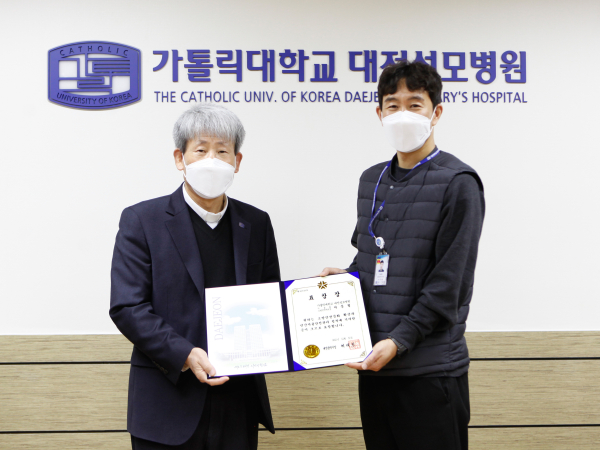 가톨릭대학교 대전성모병원 김용남 병원장이 소방안전문화 확산과 민간자율안전관리 정착에 기여한 공로로 대전광역시장 표창장을 수상한 시설팀 서문철 파트장에서 상장을 대신 전달한 뒤 기념촬영