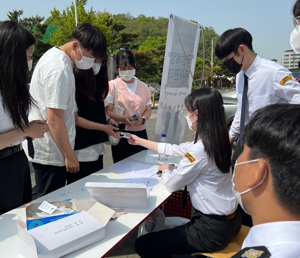 대덕대 이공관 앞에서 호우회 학생들이 재학생들에게 나라사랑큰나무 배지를 나눠주고 있다.