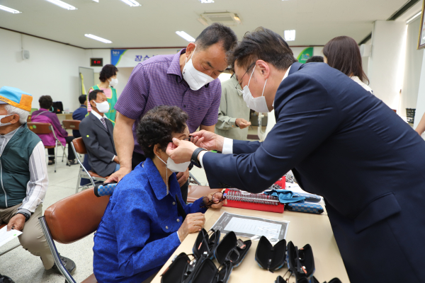 이종욱 충남세종농협본부장(오른쪽)과 임권영 광석농협조합장(왼쪽 뒤)이 농업인행복버스에 참가한 농업인에게 돋보기를 끼워드리고 있다.