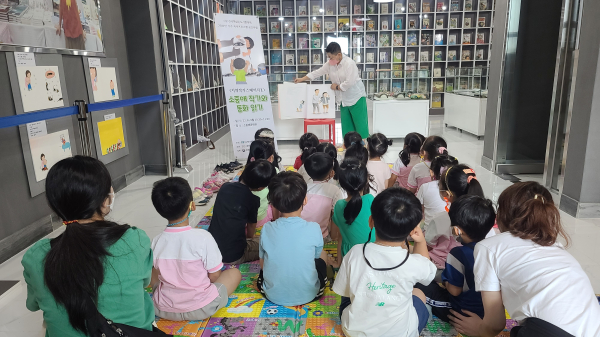 엔젤유치원생 아이들이 소중애 작가와 동화책을 읽고 있다.