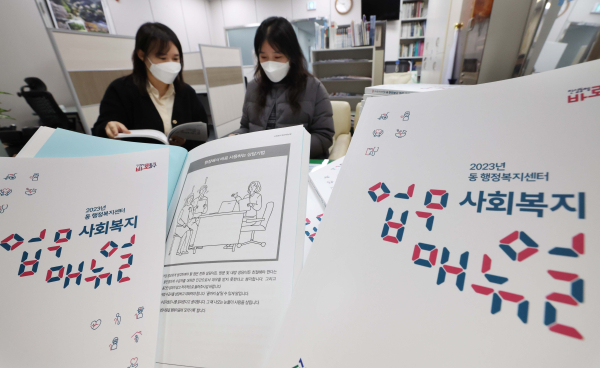 동구청 생활보장과 직원들이 배부 예정인 2023년 동 행정복지센터 사회복지 업무 매뉴얼을 살펴 보고 있다.