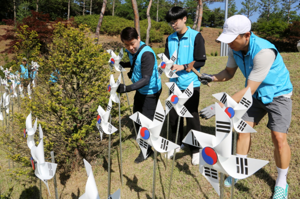 현대제철,호국보훈의 달 맞아 나라사랑공원 방문,가족봉사단이 400개의 태극기 바람개비를 설치하고 있다