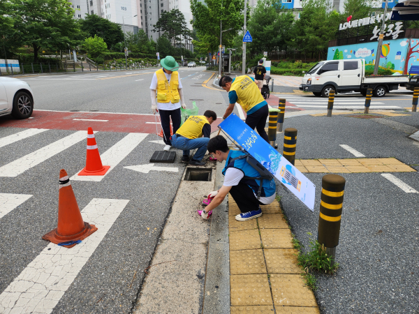 노은3동 자원봉사단체 ‘청정보안관’이 빗물받이 오염물을 제거하고 있다.