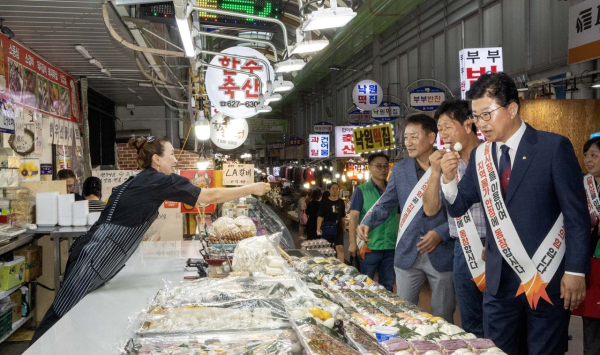 최충규 대덕구청장(사진 오른쪽)이 중리시장에 방문해 시장 상인이 나눠준 떡을 맛보고 있다.