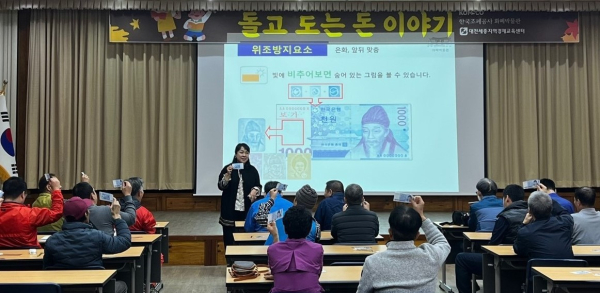 재능기부강사가 정신장애인재활시설 소속 장애인들에게 실물 경제생활에 도움 되는 화폐 위변조방지요소를 설명하고 있다.