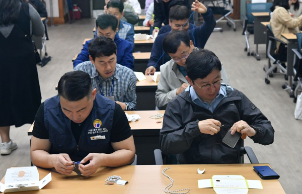 성창훈 사장(앞줄 오른쪽)과 김홍락 노조위원장(앞줄 왼쪽)이 취약계층 아동에게 전달할 핸즈온 봉사키트(가죽 카드게이스)를 손수 만들고 있다.