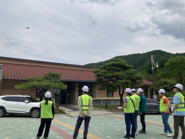 진흥원 합동 점검반원이 국립산림치유원에서 드론(좌측 상단)을 활용하여 접근이 어려운 건축물 지붕부를 점검하고 있다.
