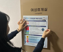 교육청 관계자가 근로자 휴게실에 산업안전보건 포스터 게시하고 있다.