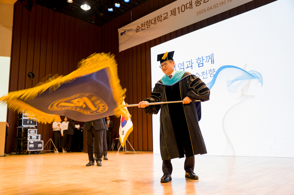 송병국 총장이 서교일 이사장으로부터 교기를 인계받아 흔들고 있다.