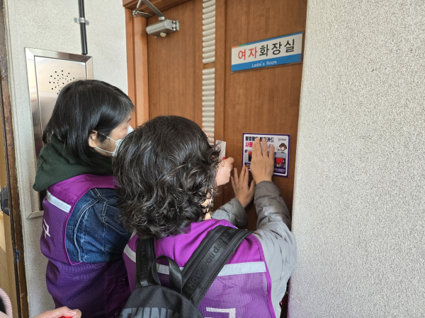 주민참여단이 행정복지센터 화장실에 불법촬영 탐지카드를 설치한 후 사용 방법 안내문을 부착하고 있다