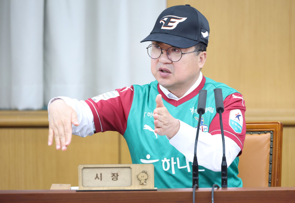 이장우 대전시장이 대전 연고 프로축구 구단 하나시티즌 유니폼과 프로야구 구단 한화이글스 모자를 착용하고 주간업무회의를 하고 있다.