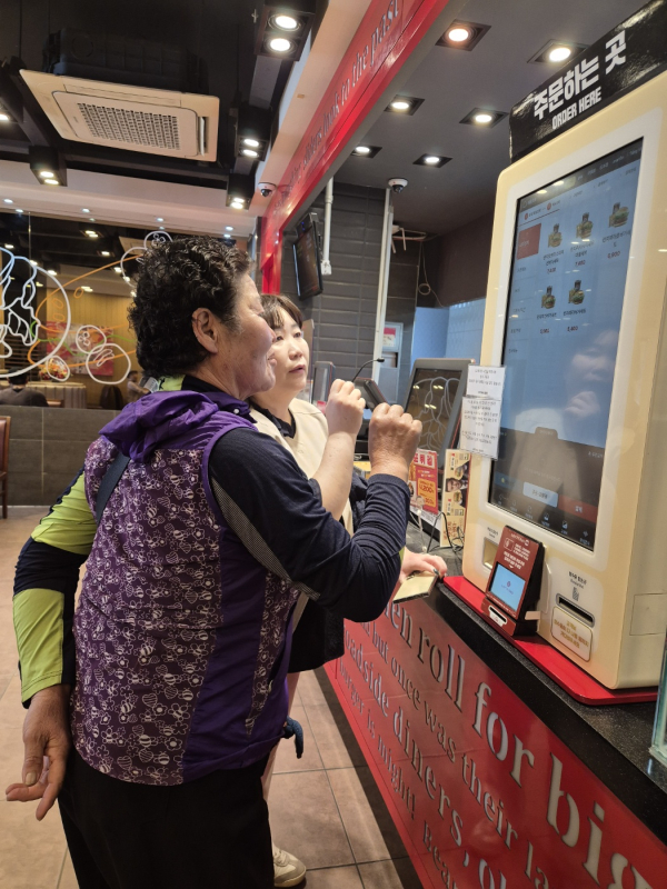 문해교실 학습자가 키오스크 앞에서 실습을 하고 있는 모습