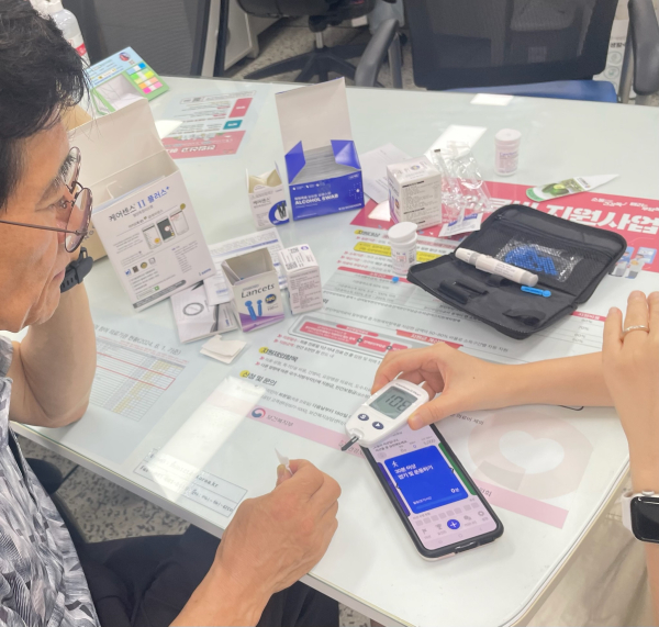 어르신 건강관리사업 참여자가 기기 사용법을 설명받는 모습