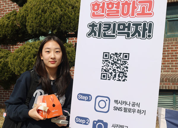 헌혈에 참여한 학생들이 시식용 치킨과 쿠폰을 전달받으며 생명나눔 캠페인에 함께하고 있다.